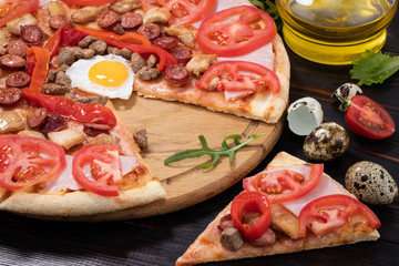 pizza with egg, ham, meat and tomatoes on wooden background