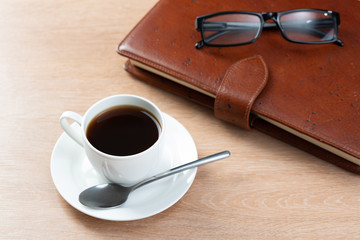 Brown leather notebook and glasses on table