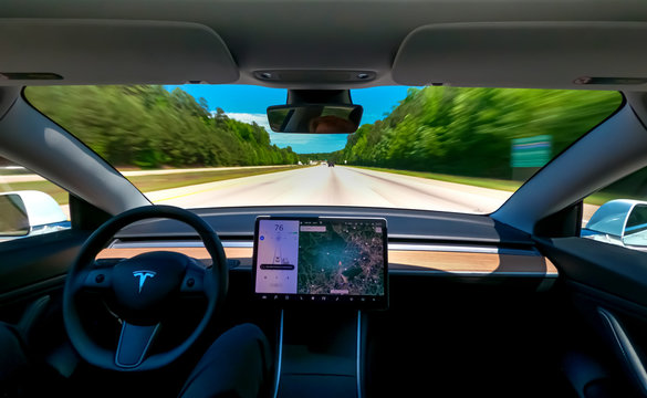 Person driving a new Tesla Model 3 on autopilot