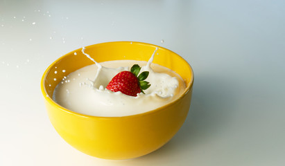strawberry falling on bowl of milk
