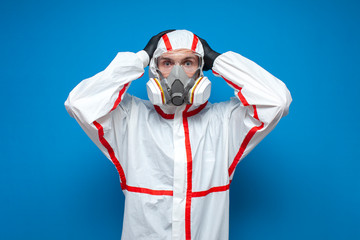 coronavirus pandemic, shocked disinfection worker in protective suit and respirator is panicking, virologist on blue background