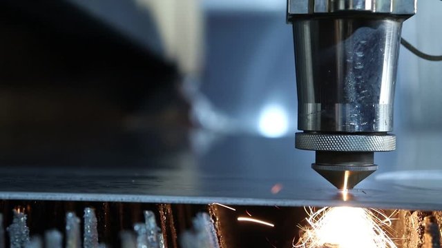 The laser machine, laser burns through a thick sheet of metal and cuts round and oval holes. Shooting with a maximum camera approximation and with the use of "panoramic tracking".