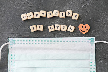 quarantine is over incription. end of quarantine concept. medical face mask and letters on dice...