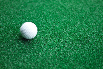 Side view of a golf ball lying on an green lawn.