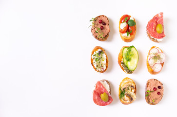 Assorted italian appetizer bruschetta or tapas set with different savory and on white concrete background.Top view,copy space