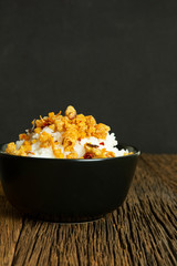 Chili paste fried pork skin and rice in black cup on wood table have dark background