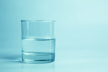Half glass of water on a white background with a shadow below