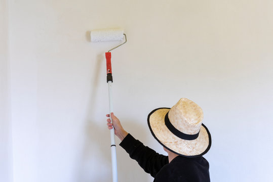 Pintor pintando una pared blanca con rodillo de pintura