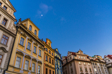 Fototapeta na wymiar Row of buildings with colorful facades in Prague Old Town (Stare Mesto) historical city centre on Old Town Square Staromestske namesti in evening, blue sky and moon background, Bohemia, Czech Republic