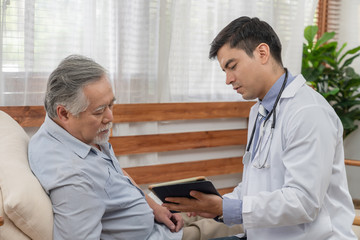 Doctor explaining health examination results with elderly patient at home visit