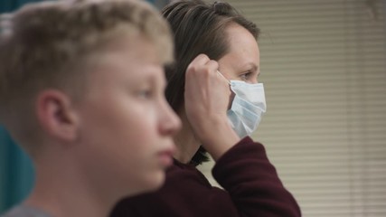 A side view slow motion portrait of a teacher and her student putting medical masks on their faces in turns before starting practising their musical skills