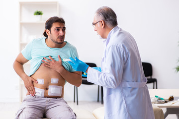 Obraz premium Injured young man visiting experienced male doctor