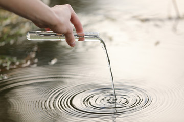 Pond water pollution concept. Scientist biologist and researcher takes samples of dirty water from...