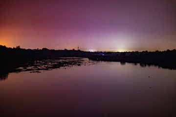 Obraz premium Night view of river side with little lights in the background of a town...