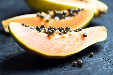 Slised papaya with silver spoon on black concrete background. Food photography