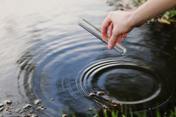 Scientist and biologist hydro-biologist takes water samples for analysis. Hand is collects water in...