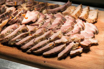 baked pork stuffed with carrots, sliced into thin slices on a wooden board. juicy slices of cooked meat close-up.