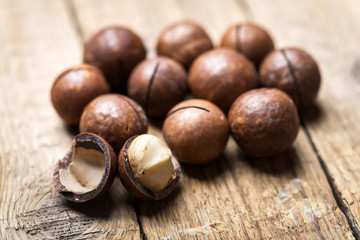 Dried organic Macadamia nuts on wooden table. Studio macro shoot. Black concrete background