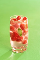 Glass of water and frozen fruits. Iced raspberries.
