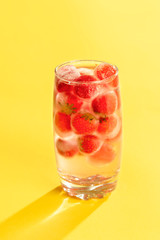 Frozen strawberries in a glass of water. Cold summer drink