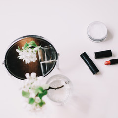 Blossom flowers, cosmetics and a mirror on the dressing table top view. Flat lay with women accessories. Cosmetic composition.  