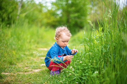 Little girl plays on nature against the background of spring greenery.
