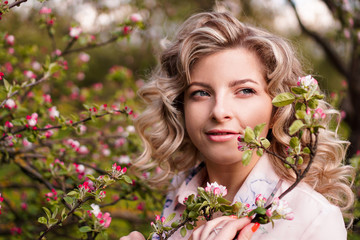 Fototapeta premium Romantic young woman in the spring garden among apple blossom. Beautiful woman, happy spring
