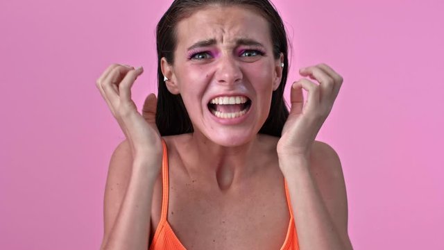 Young stressed screaming woman isolated over pink wall posing background