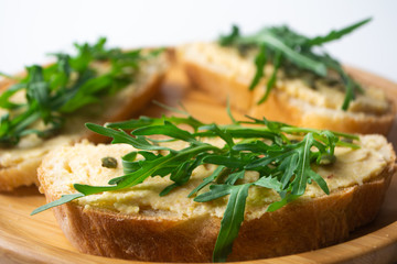 Sandwich of toasted bread slices with classic chickpea hummus spread, roasted pumpkin seeds and fresh arugula