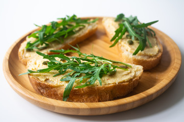 Sandwich of toasted bread slices with classic chickpea hummus spread, roasted pumpkin seeds and fresh arugula