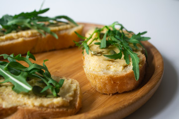 Sandwich of toasted bread slices with classic chickpea hummus spread, roasted pumpkin seeds and fresh arugula