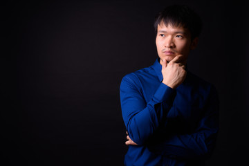 Portrait of young Asian businessman thinking and looking away