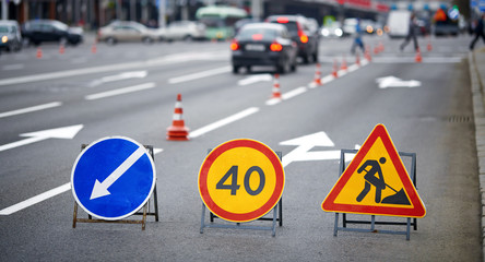 Road marking on the road, warning signs and orange safety cones on background. Direction of detour, sign speed limit 40 and roadworks. Road signs denoting road repairs, speed limit up to 40, detour