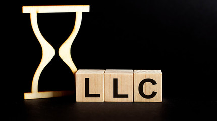 Wooden blocks LLC with sand clock on table. Personal, career or business development, mindset...