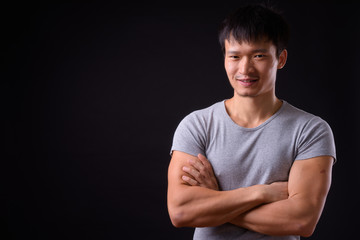Portrait of happy young Asian man smiling with arms crossed
