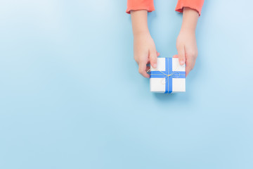 Father's day or birthday concept. Kid gives gift box to father on light blue pastel background with copy space. Top view, flat lay.