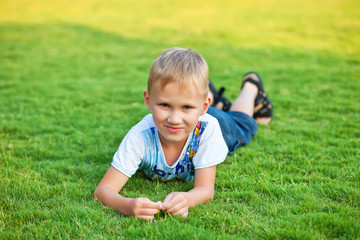 Portrait of a smiling boy lying on green grass.