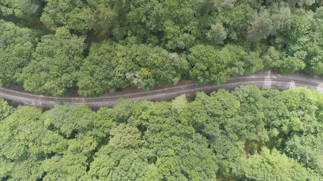 AERIAL DRONE TOP DOWN BACKWARD UP 360 DEGREE SHOT OF EMPTY RAILWAY TRACK IN THE WOODS, S SHAPED. 