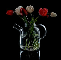 glass teapot with flowers on a black background