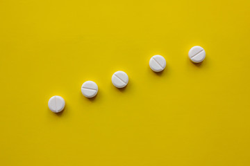 White pills on a yellow background.