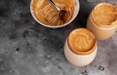 Popular drink Korean dargon coffee made of instant coffee, sugar, hot water and milk in glass on grey background. Cope space