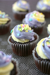 Top view of yellow and purple easter cupcake on lined background