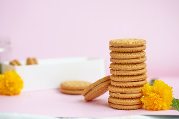 round homemade cookies stacked in a stack in a white box with vanilla cream on a light pink background.