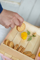round homemade cookies in a wooden box with vanilla cream on a light pink background.