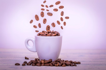 Coffee beans falling in white cup. Highspeed shot. Roasted coffee beans falling into coffee cup on saucer with white background, fresh energy wallpaper concept.