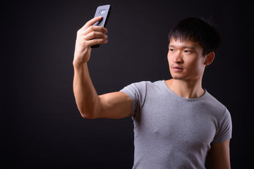 Portrait of young Asian man taking selfie with phone