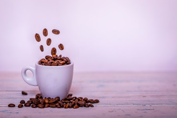 Coffee beans falling in white cup. Highspeed shot. Roasted coffee beans falling into coffee cup on saucer with white background, fresh energy wallpaper concept.