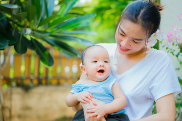 Happy woman and child in the blooming spring garden.baby with his mother enjoying a home outdoors. Mothers day holiday concept