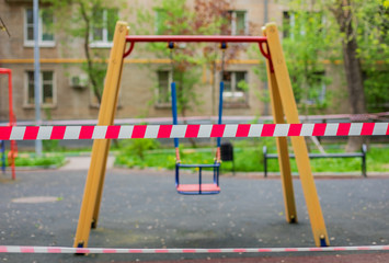 A swing at a playground in the city is fenced with a signal red and white ribbon during the Covid-19 coronavirus pandemic. Self-isolation.