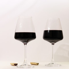 a pair of insulated glasses with red wine on a white background
